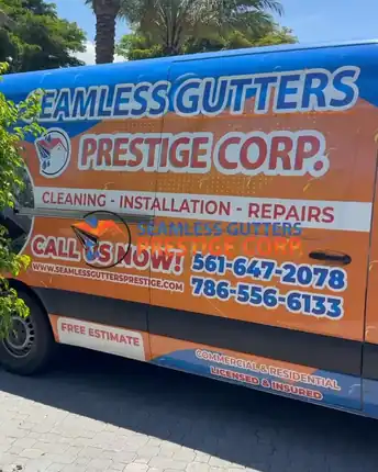 The sign written Prestige Seamless Gutters van parked on a paver driveway, listing cleaning, installation and repairs